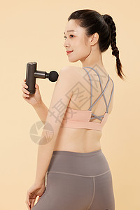 健身美女用筋膜枪放松肌肉背景图片