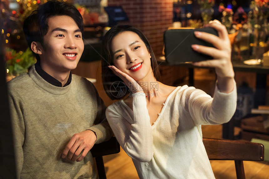 餐厅内的青年伴侣使用手机自拍图片