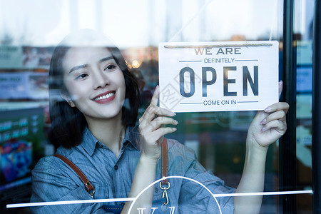 咖啡店门口咖啡店的女服务员挂营业标志背景