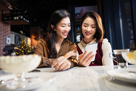 年轻闺蜜在咖啡馆使用手机高清图片