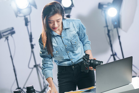 电脑器材在工作室里的青年女摄影师背景