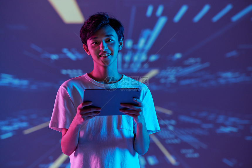 虚拟背景下的男青年手拿平板电脑图片