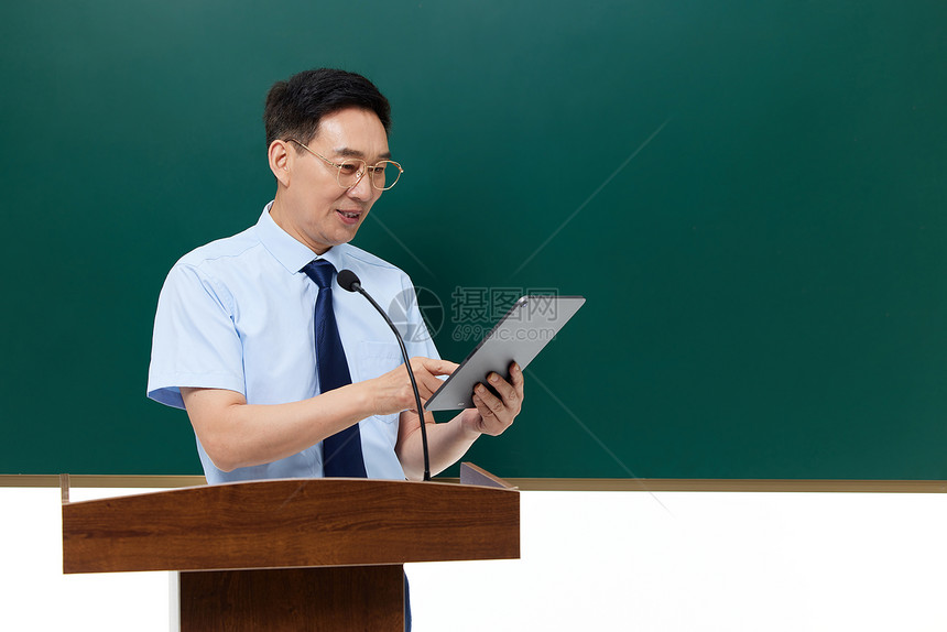 男教授手拿平板电脑在讲台上讲课