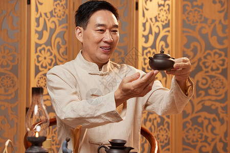 中年男茶艺师鉴赏茶壶图片