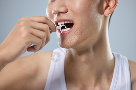 年轻男性使用牙线清洁牙齿特写图片