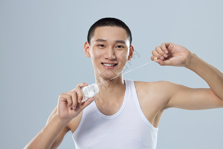 使用牙线清洁牙齿的年轻男性图片