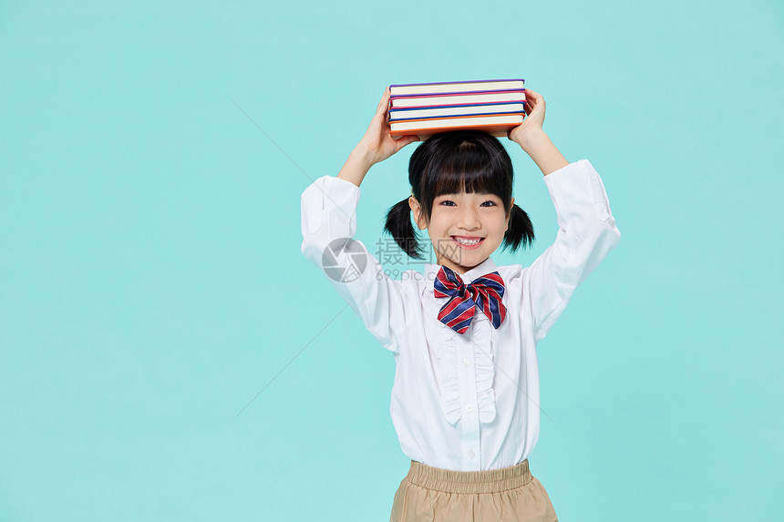 头顶书本笑容灿烂的小女孩图片