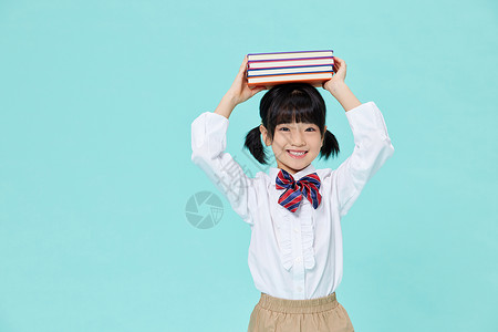 头顶书本笑容灿烂的小女孩高清图片