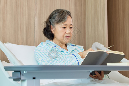 生病住院的老年女性看书阅读背景图片