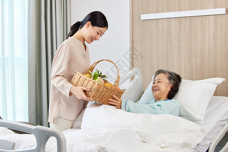 手拿果篮的女性探望生病住院的老人女儿高清图片素材