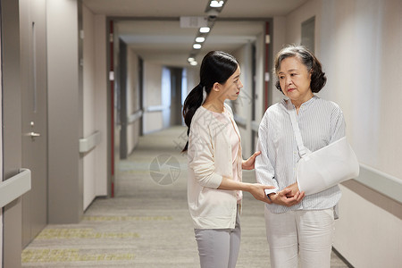 老人年医院走廊上青年女性搀扶骨折的老人背景
