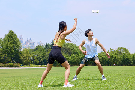 城市竞技赛公园里年轻男女玩飞盘背景