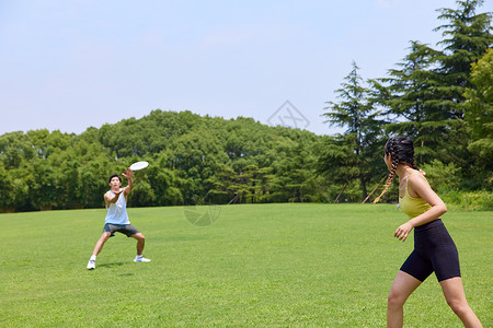 青年男女在户外公园玩飞盘高清图片