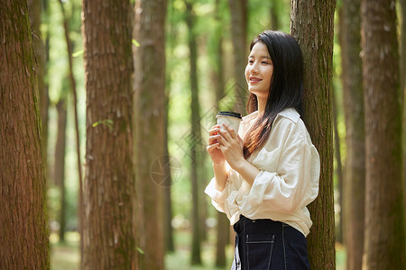 在树林里手拿咖啡的美女背景图片