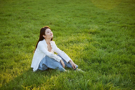 初秋在草坪上休闲的年轻女性背景图片