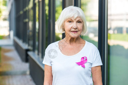 老年女性佩戴着粉色丝带宣传癌症背景图片