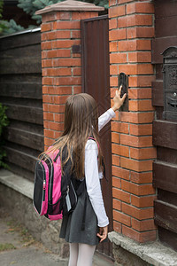 穿着校服的小女孩背着书包敲门铃图片