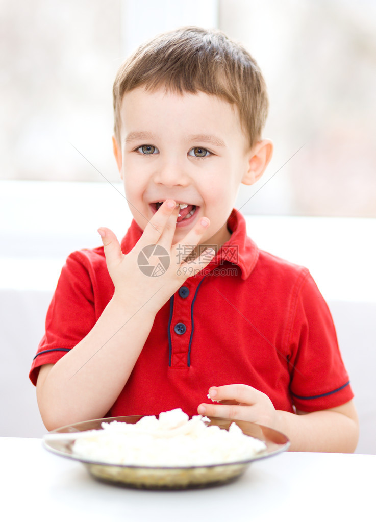 可爱的小男孩正在用勺子吃奶酪图片