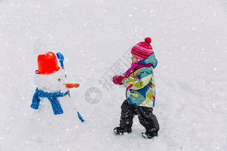 小女孩在冬天雪地里堆雪人图片