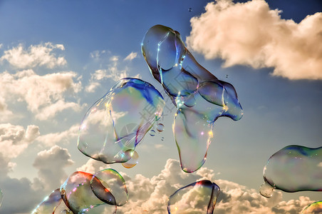 天空和云彩背景上的彩色肥皂泡图片