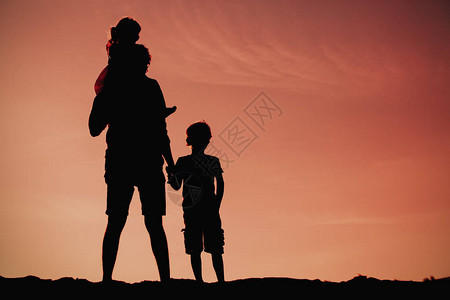 父亲和儿子与女儿在日落海滩散步图片