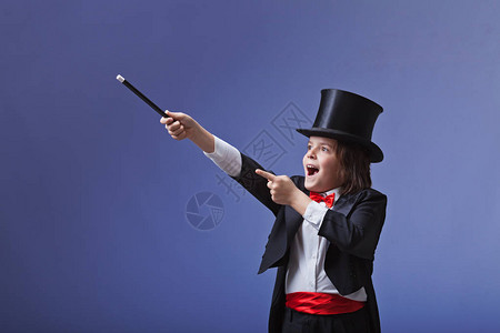 年轻的魔术师用魔杖表演图片