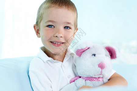 一个可爱的男孩抱着他的泰迪熊的特写肖像图片