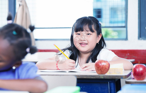 亚洲女孩在课堂桌上微笑在学校上课时图片