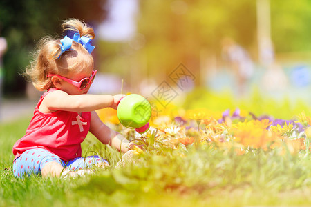 可爱的小女孩在夏天给花浇图片