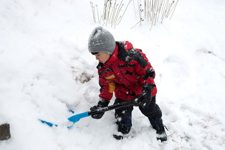 一个小男孩正在铲雪背景图片