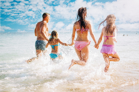 幸福的家庭在海滩上玩得开心他们手牵跑图片