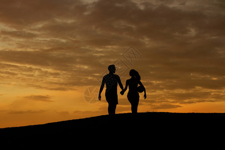 恩爱的情侣在傍晚的小山上散步恩爱夫妻的剪影丈夫和妻子晚上散图片