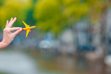 在街道背景上一只手拿着黄色飞机模型图片