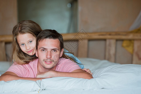 男人带着小孩坐在床图片
