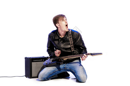 年轻的英俊摇滚音乐家演奏电吉他和歌图片