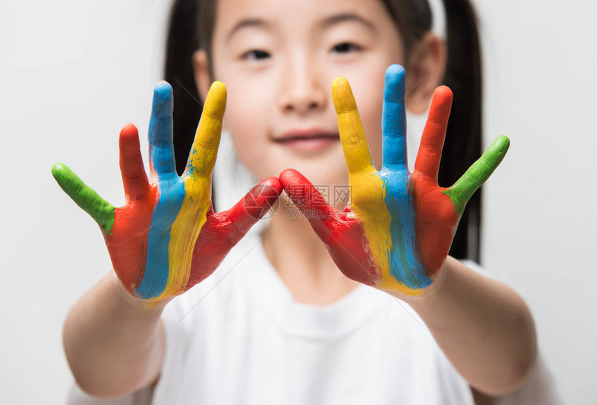 手涂着五颜六色的颜料的亚洲小女孩图片