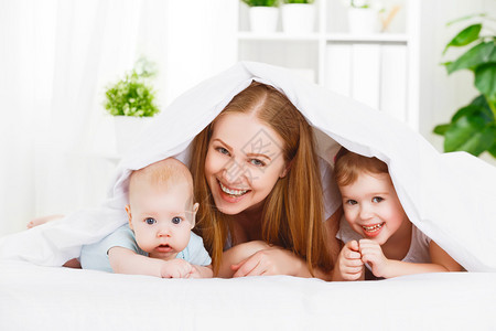 幸福的家庭母亲和两个孩子儿子和女儿在床图片