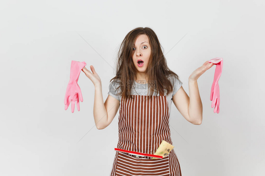 年轻有趣的疯狂头晕疯子狂野尖叫的家庭主妇用条纹围裙刮板清洁抹布在白色背景上隔离的口袋里弄乱头发疯女人和粉红手套