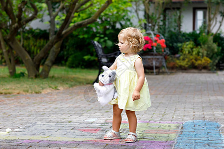 可爱的蹒跚学步的小女孩和最喜欢的软毛绒玩具狗在户外玩耍可爱的宝在后院或花园里美丽背景图片