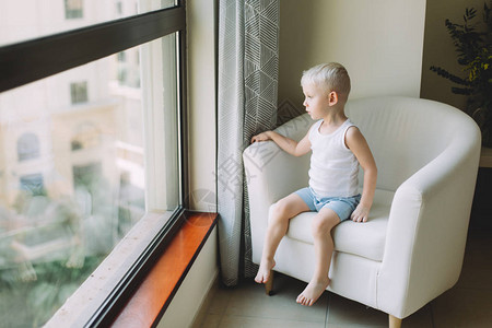 坐在沙发上看着窗子的可爱小男孩的肖像他图片
