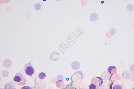 白色表面上散落的紫色五彩纸屑的顶部视图图片
