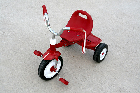 水泥背景上一辆空荡的红色三轮车图片
