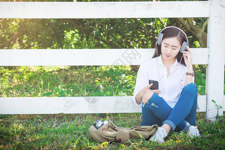 可爱清纯的女士坐在草地上听音乐图片
