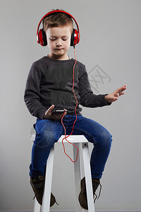 有趣的孩子戴耳机的小男孩坐在椅子上时尚图片