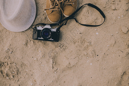相机和鞋子在沙滩上戴着白帽子图片