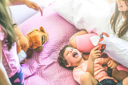 快乐的家庭孩子在床上玩具和枕头图片