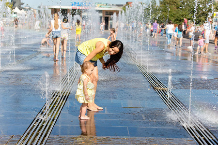 母亲和儿童在喷泉玩水图片