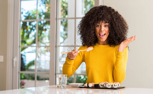 在家中用筷子吃寿司的非裔美国妇女非常快乐和兴奋图片