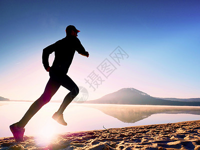 男人在日出时在沙滩上晨跑锻炼图片