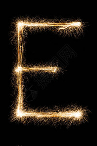 英文大字母E由黑色背景上的燃烧火花制成闪亮的节日派对烟花字体背景图片